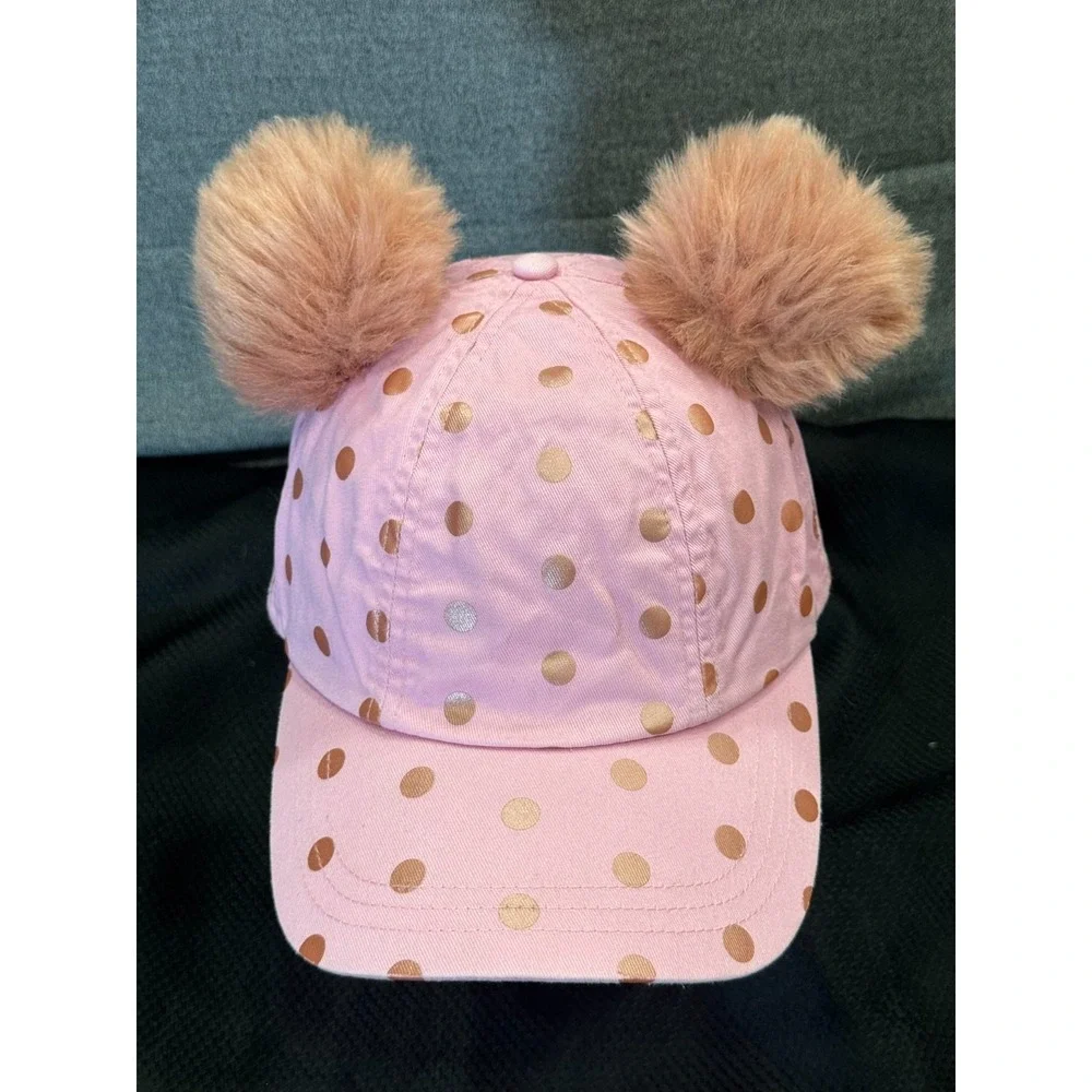 Pink polka-dot cap topped with two fluffy faux fur pom poms